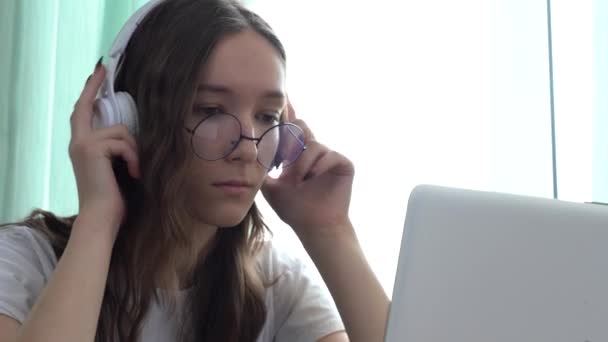 Chica caucásica seria con auriculares y viendo un curso de video educativo con su computadora portátil — Vídeos de Stock