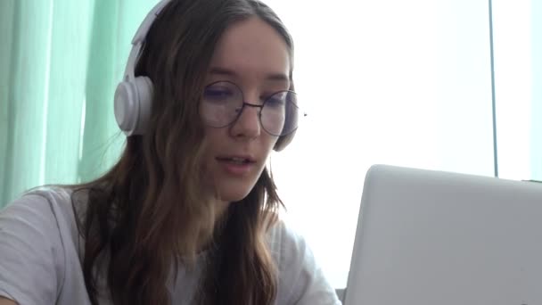 Étudiante portant un casque étudiant en ligne avec un professeur d'Internet, regardant un ordinateur portable — Video