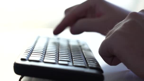 Een man begint te typen op een toetsenbord. Een close-up. Zijaanzicht. Langzame beweging — Stockvideo
