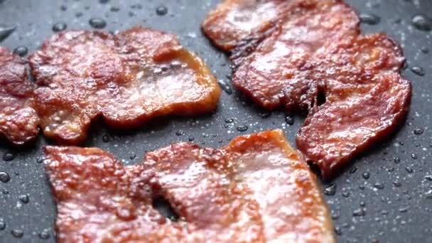 Freír las piezas de tocino en una sartén. Trozos crujientes de Delicious Bacon se fríen en una sartén caliente. Tiras de tocino, fritas en una sartén — Vídeos de Stock