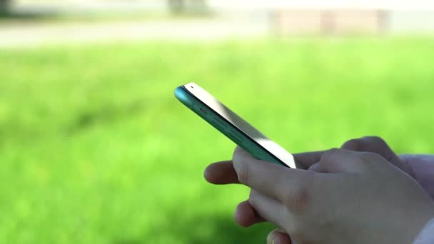 Een close-up. Gebruik een smartphone in het park. Gebruik van mobiele telefoon door vrouwen in stadspark — Stockvideo