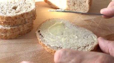 Ekmeğe tereyağı sür. Yavaş hareket eden bıçak, ekmek yüzeyine tereyağı sürüyor. Yakın plan.