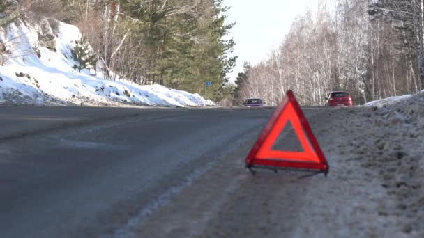 Czerwony Trójkąt Ostrzegawczy na zimowej drodze w lesie. Problemy z podróżowaniem samochodem w zimie — Wideo stockowe