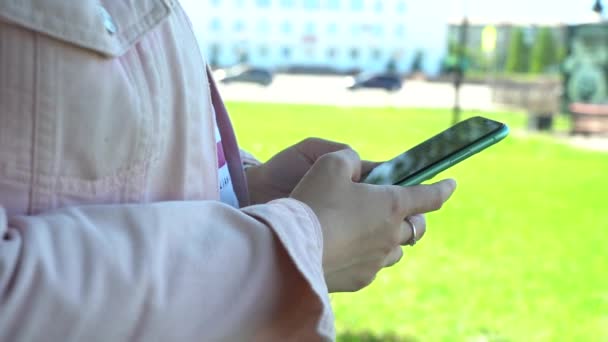 Zbliżenie. Użyj smartfona w parku. Kobieta korzystająca z telefonu komórkowego w parku miejskim — Wideo stockowe