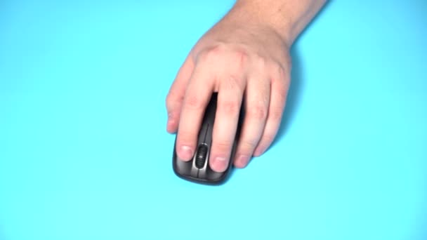 Izolováno na světle modrém pozadí. Levá ruka drží bezdrátovou myš na stole. Klik a pohyb — Stock video