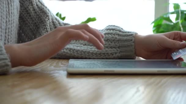 Fille tenant une disposition de carte de crédit et utilisant un ordinateur tablette tout en étant assis dans un café — Video