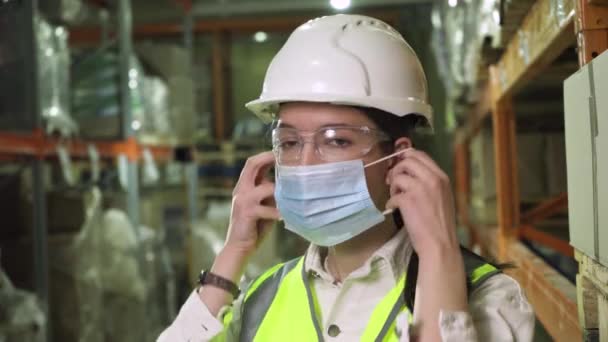 Retrato de una trabajadora con un chaleco protector, sombrero duro, con una máscara médica — Vídeo de stock
