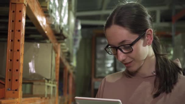 Primer plano de un joven empleado con una tableta de ordenador, trabajando en el almacén — Vídeos de Stock