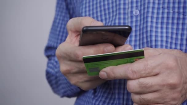 Gros plan des mains de l'homme tenant une carte de crédit et utilisant un smartphone. — Video