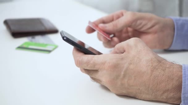 Händerna på en man som, med en smartphone, ett kreditkort, gör en lyckad betalning — Stockvideo