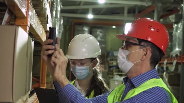 Engenheiros masculinos e femininos em capacetes, coletes e máscaras verificando caixas de armazenamento — Vídeo de Stock
