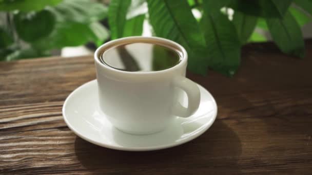 Horká káva v bílém šálku na pozadí dřeva — Stock video