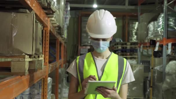 Egy biztonsági mellényt, keménykalapot és arcmaszkot viselő női felügyelő egy gyárban végzett ellenőrzés során. — Stock videók