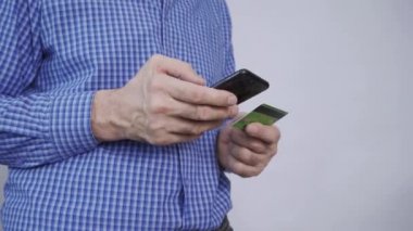 Kredi kartı tutan ve akıllı telefon kullanan erkeklerin yakın çekimi..
