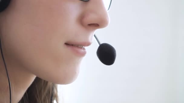 Primer plano de la cara de una joven con auriculares, que se comunica en línea, explica, enseña. — Vídeos de Stock