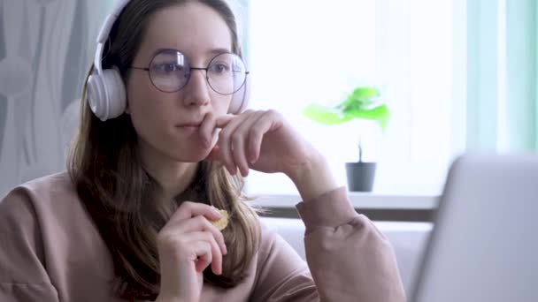 Une fille à la maison regardant une émission en ligne et rongeant sur les cookies — Video