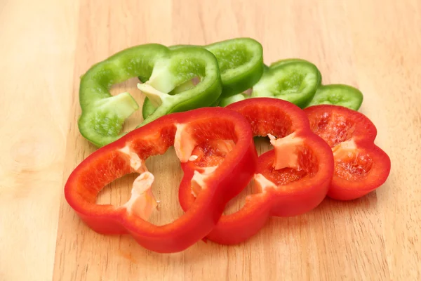 Sliced red and green sweet peppers on a wooden board — Stock Photo, Image