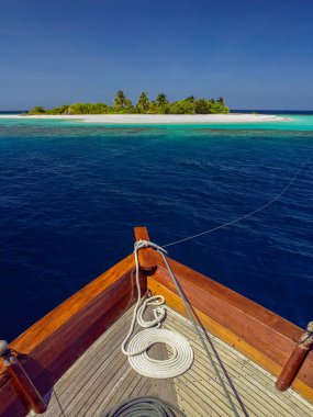 Küçük ıssız bir adanın ve Maldivler 'deki Güney Ari mercan kayalıklarının yakınındaki yat, Hint Okyanusu.