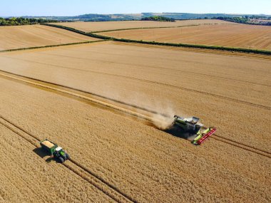 Aerial view of a combine harvester in a landscape of wheat fields on farmland in North Yorkshire in the United Kingdom.
