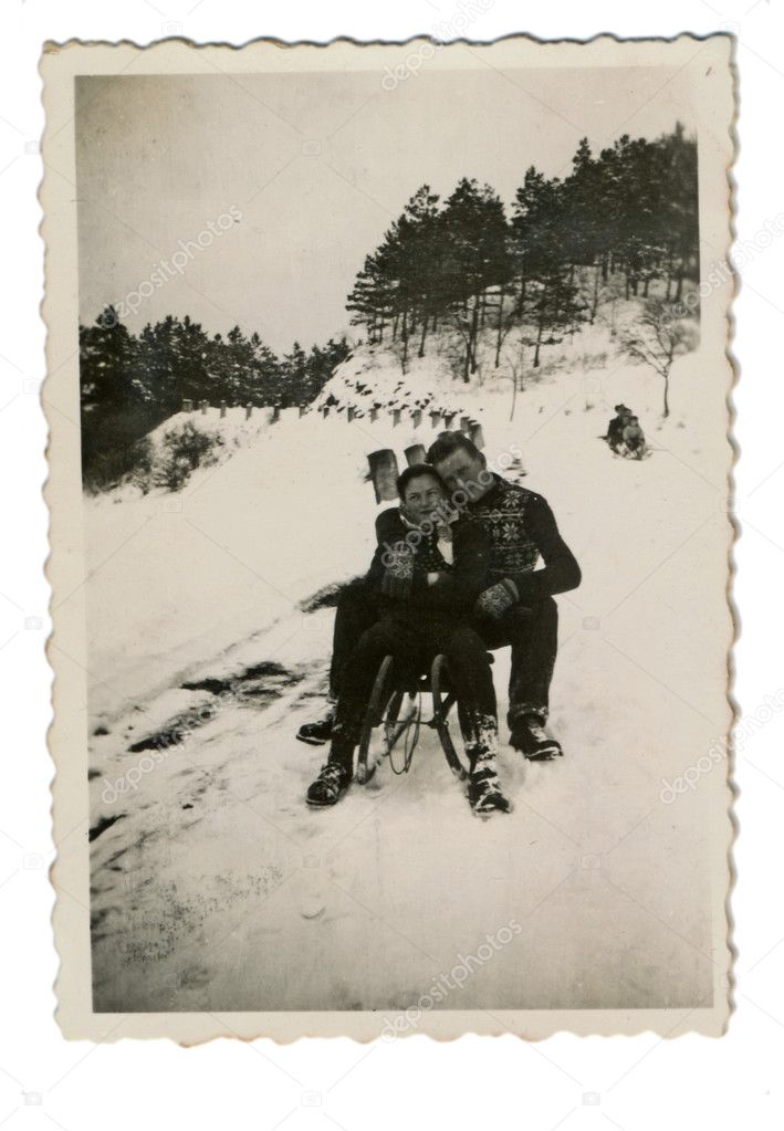 Winter holidays - man and woman on a toboggan