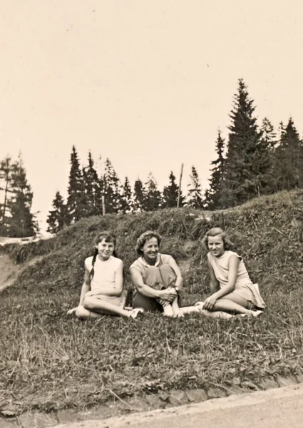 Drie meisjes zitten in een weide — Stockfoto