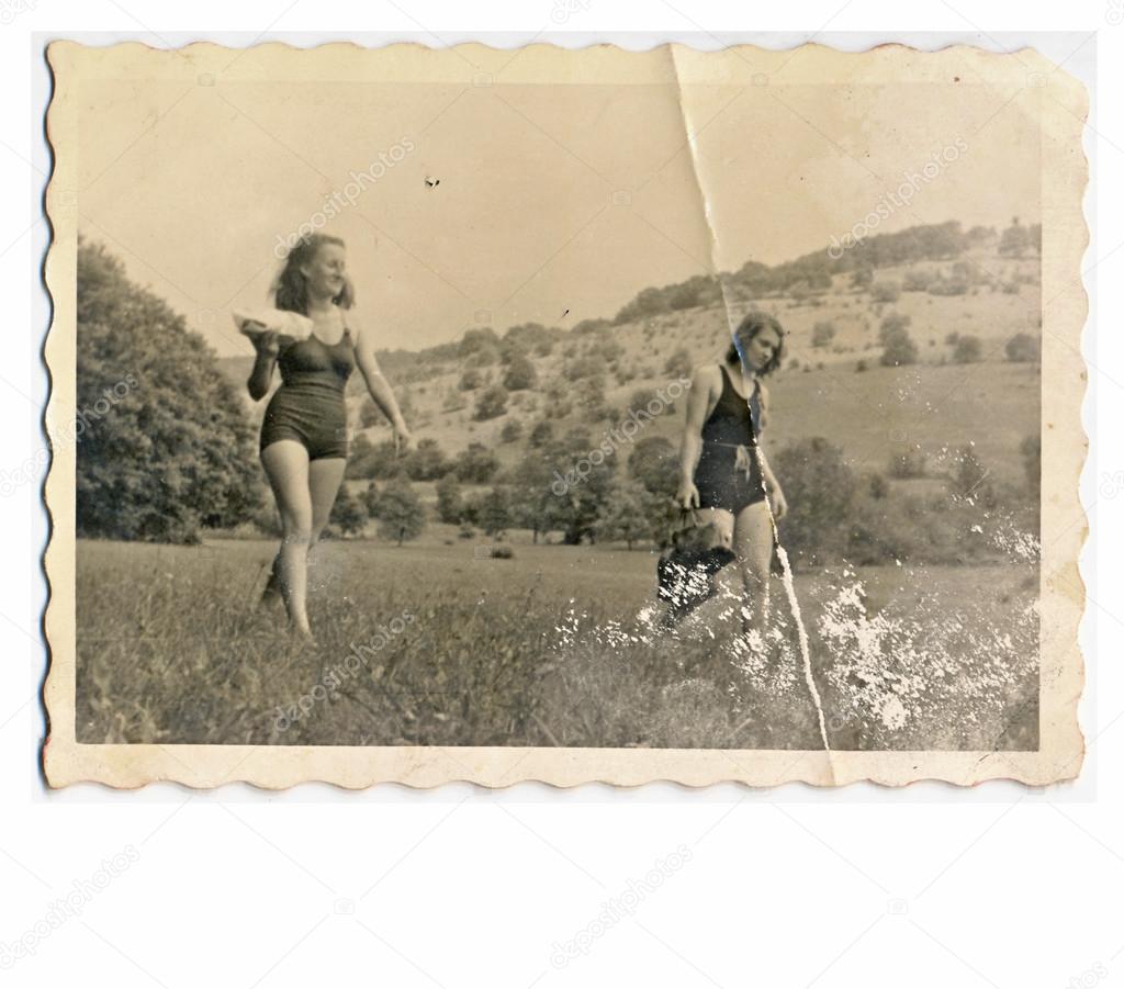 Friends - Two young women in bikini (walking through the meadow)