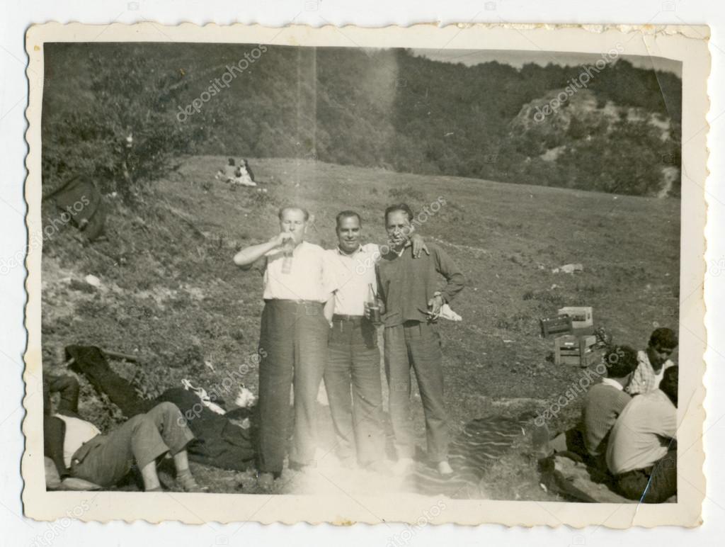 Men standing in a field and drinking