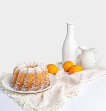 Beyaz peçeteli kek, iki mandalina ve beyaz arka plan.