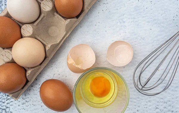 Raw eggs in package and whisk on kitchen table. High quality photo