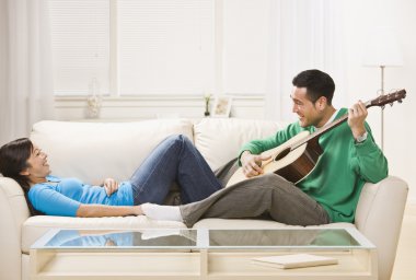Asian couple on couch relaxing together. clipart