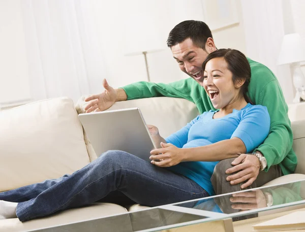 Casal rindo enquanto olha para um laptop juntos — Fotografia de Stock