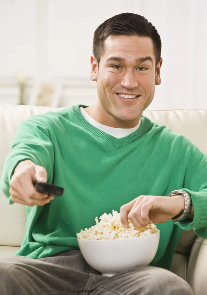 Attraente uomo asiatico con popcorn e telecomando — Foto Stock