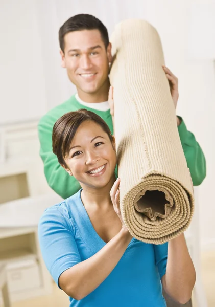 Glückliches Paar trägt Teppichrolle — Stockfoto