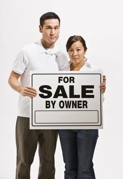 Besorgtes Paar hält Schild zum Verkauf — Stockfoto