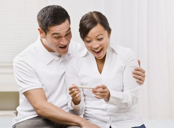 Casal extático olhando para um teste de gravidez juntos . — Fotografia de Stock