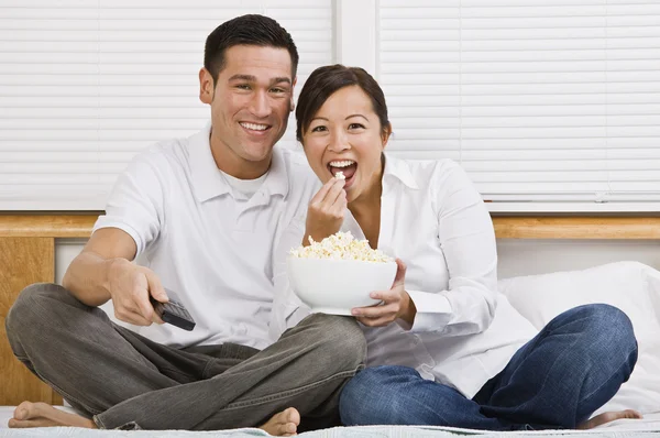 Atractiva pareja asiática comiendo palomitas en la cama —  Fotos de Stock