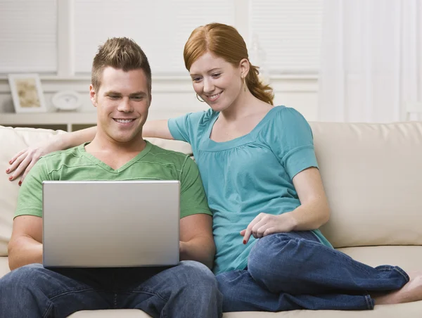 Paar schaut gemeinsam Laptop auf der Couch — Stockfoto