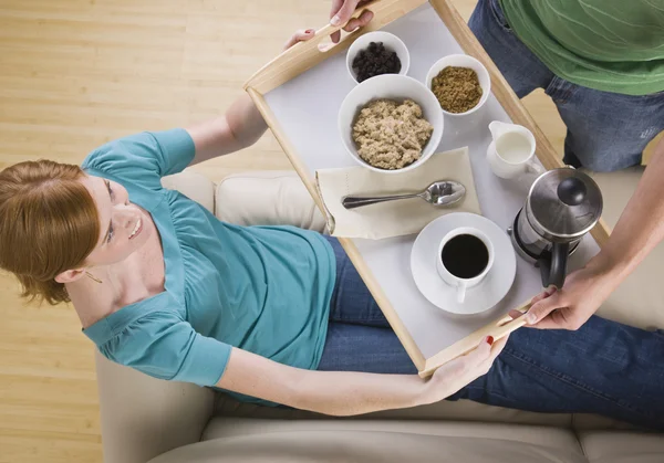 Attractive woman being served breakfast on the couch. — Stock Photo, Image