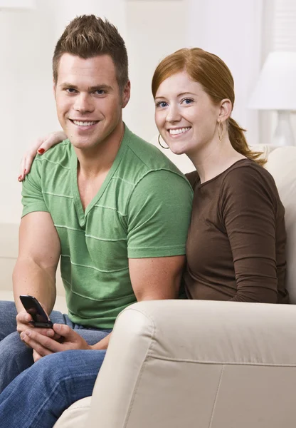 Atractiva pareja de jóvenes sentados juntos en el sofá —  Fotos de Stock