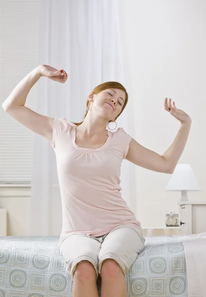 Vrouw die zich uitstrekt op haar bed — Stockfoto