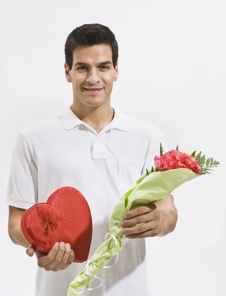 Hombre feliz sosteniendo dulces y flores — Foto de Stock