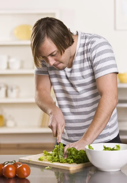 Attractive male cutting lettuce — Stock Photo, Image