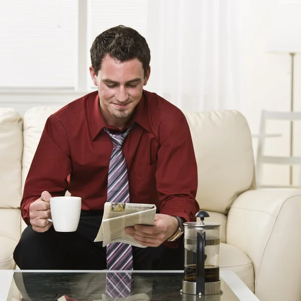 Aantrekkelijke man drinken koffie en het lezen van een krant — Stockfoto