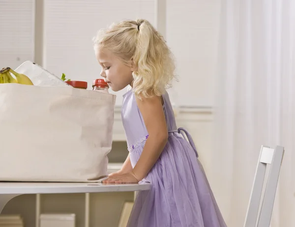 Chica espiando en bolsa de comestibles — Foto de Stock