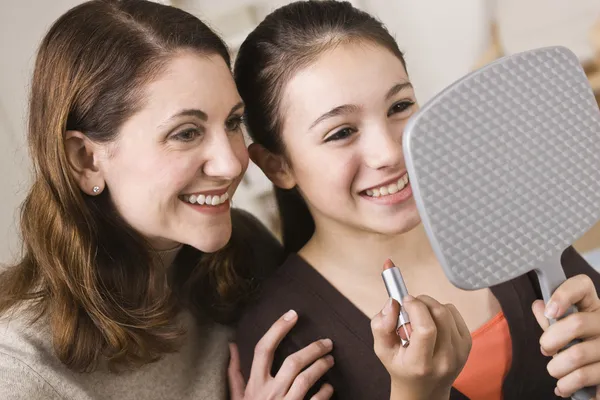 Madre e hija sonrientes con lápiz labial, mirando el espejo — Foto de Stock