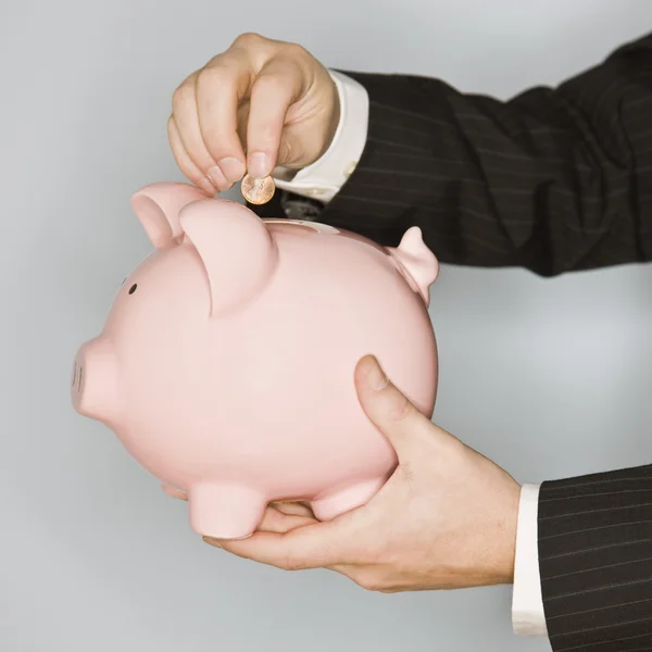 Man Putting Coin in Piggy Bank — Stock Photo, Image