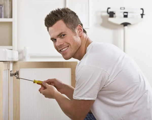 Smiling Man Fixing Cabinet Door — Stock Photo, Image