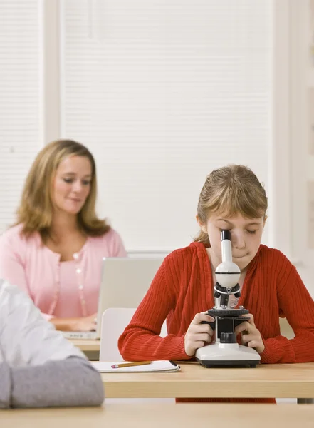 Student op zoek naar de Microscoop in klas — Stockfoto