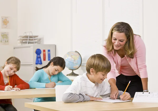 Teacher helping student in classroom — Stock Photo, Image