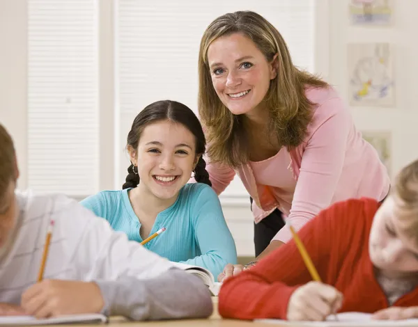 Teacher helping student in classroom — Stock Photo, Image